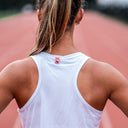 Female runner in a SA1NT LAYERS run singlet on a running track