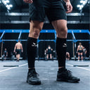 SA1NT LAYERS P1 Race Compression Calf Guards, worn in an indoor training hall