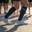 Runner wearing SA1NT LAYERS Compression Race Socks Charcoal Bright Blue at a race start line
