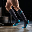 Athlete wearing SA1NT LAYERS Compression Race Socks Charcoal Bright Blue in a gym