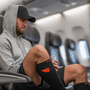 Athlete wearing SA1NT LAYERS compression socks on a long-haul flight to an overseas race